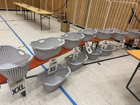 Wäschekörbe, nach Größen von XS bis XXL sortiert, in der Turnhalle